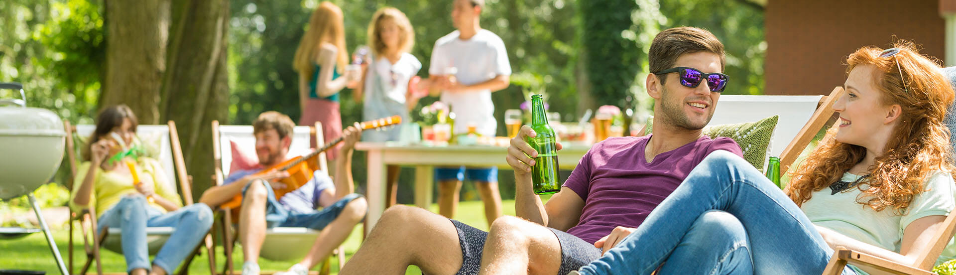 Junge Leute sitzen auf Liegestühlen im Garten