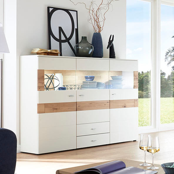 Weißes Highboard mit Absetzung aus Holz in einem Wohnzimmer stehend