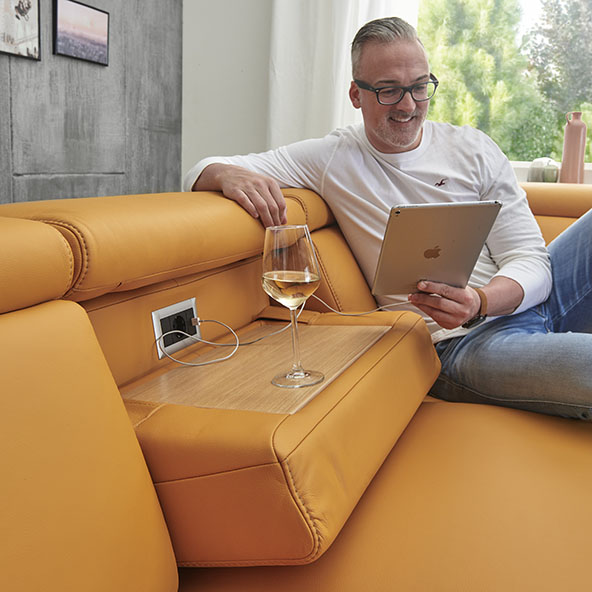 Detailbild zeigt ausklappbare Ablagemöglichkeit einer orangefarbenen Couch