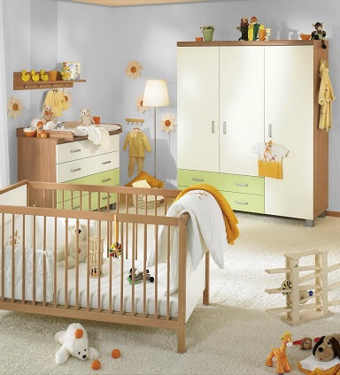GUNST-Kinderzimmer: Eine Babyzimmer mit Kommode und dreitürigem Schrank in Weiß mit abgesetzten Schubladen in Apfelgrün, Im Vordergrund ein Gitterbettchen aus der selben Möbelserie.