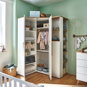 Babyzimmer-Eckschrank geöffnet, an der rechten Seite schließt sich ein Regal an, das von zwei Seiten zugänglich ist.