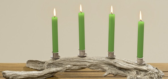 Natürlich und elegant ist dieser Adventskranz in Naturopti mit vier schlanken, grünen Kerzen auf einer Baumwurzel. 