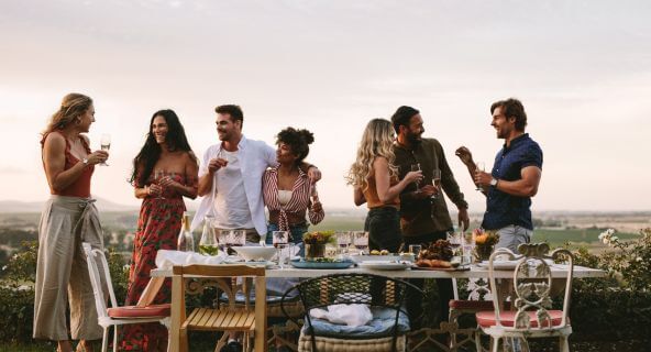 Gruppe von Menschen an einem sommerlich gedeckten Tisch im Freien
