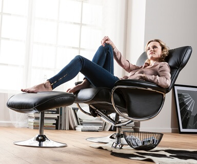 Junge Frau entspannt in einem schwarzen Relaxsessel.
