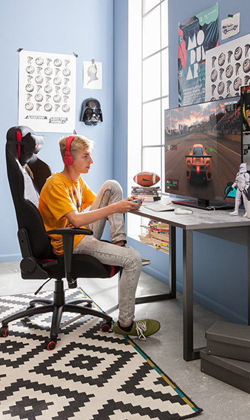 GUNST-Blog Schreibtischstühle - ein Teenager beim Gaming in einem Gaming-Stuhl mit Kopfstütze und Armlehnen.