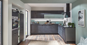 Küche mit salbeigrüner Wand und dunklen Möbeln.