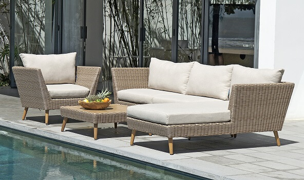 Gartenlounge-Gruppe aus hellem Polyrattan mit cremefarbenen Polstern, und passendem Tisch.