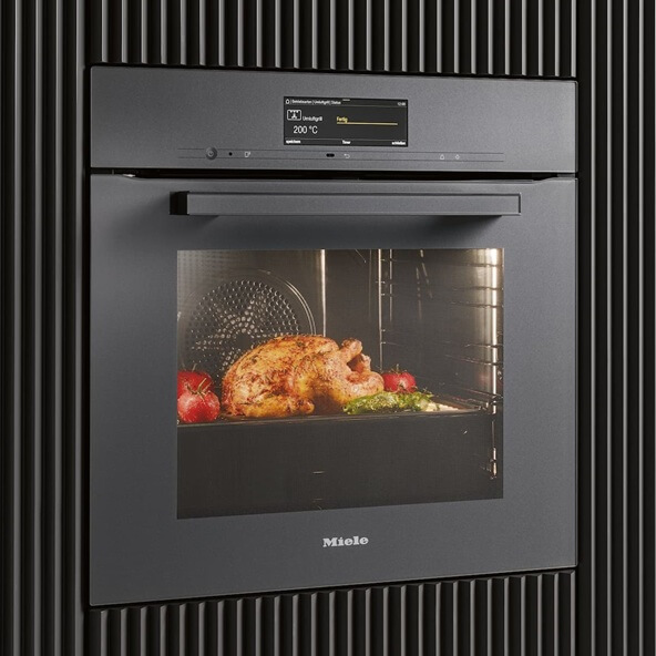 In einem Backofen mit integriertem Airfryer wird ein Grillhähnchen schonend zubereitet.