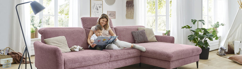 Möbel GUNST - Moodbild Wohnzimmer- eine Mutter  sitzt mit ihrem Sohn auf einer roséfarbenen Couch.