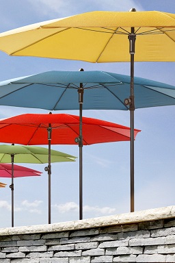 GUNST-Gartenmöbel: bunte Sonnenschirme sind hintereinander aufgespannt und stehen in einer Reihe.