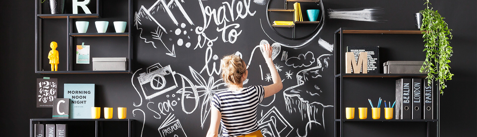 Titelbild für Blog-Artikel "Platz auf kleinstem raum. Frau nutzt  eine mit Tafellack lackierte wand als Zeichenbrett.