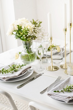 GUSNT Blog Tischdekoration - Rosenstrauß auf festlich gedecktem Tisch mit goldenen Kerzenhaltern.
 