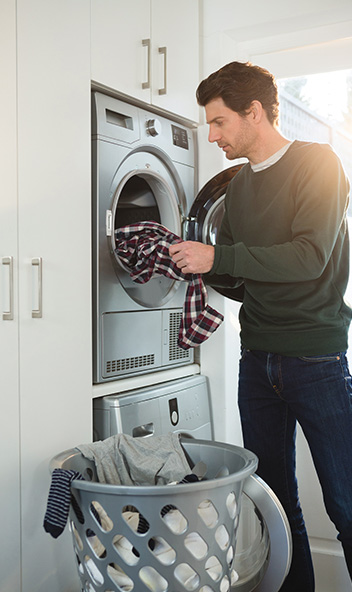 ein Mann leert eine Waschmaschine, die auf Arbeitshöhe eingebaut ist.
