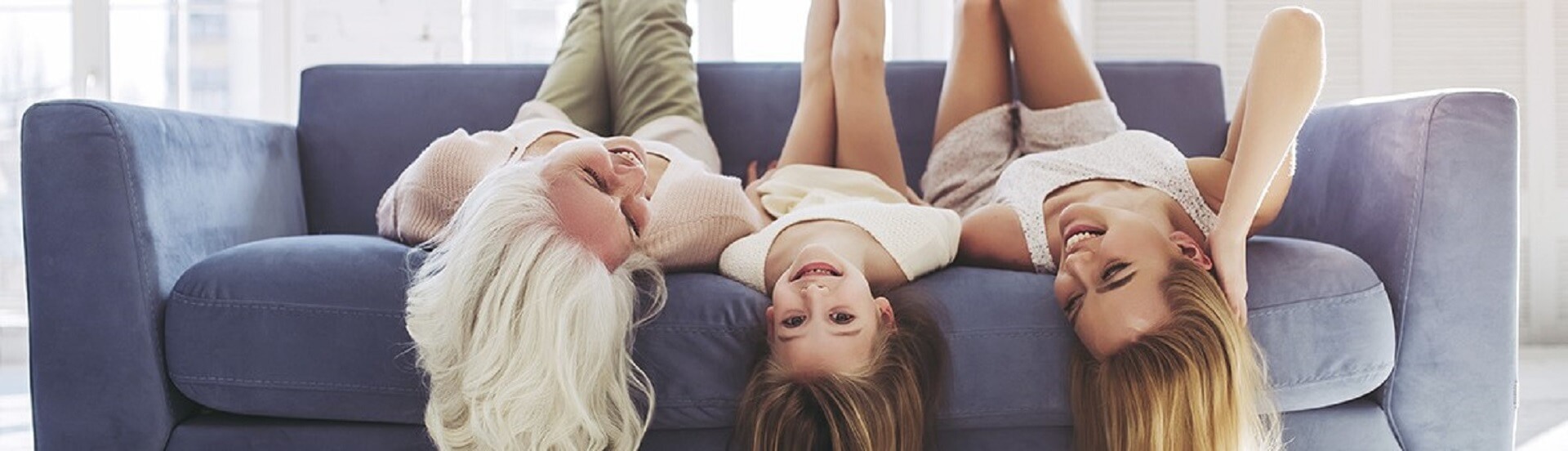 GUNST Headermotiv zum Blog-Artikel „Wohntrends 2022“; zwei Frauen und ein Mädchen liegen kopfüber lachend auf einem Sofa.
