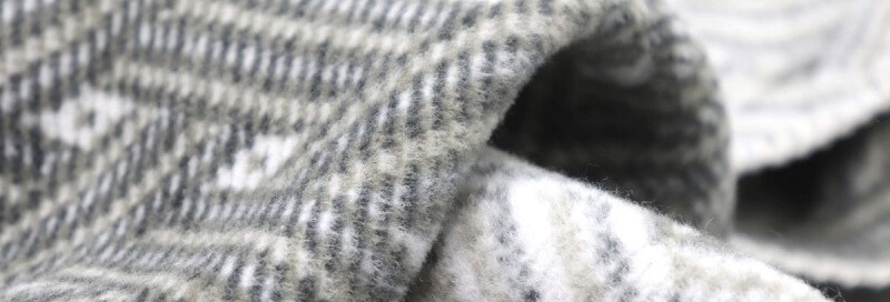 Bildausschnitt einer Kuscheldecke aus grauem Fleece-Stoff