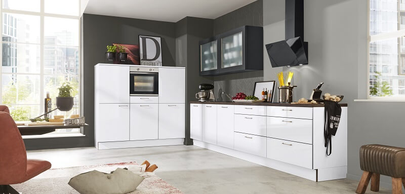 Moderne L-Küche, bestehend aus eier langen Zeile mit Arbeitsfläche, Kochfeld, Spüle und Oberschränken und einem halbhohen Schrankelement mit Backofen, Stauraum und Kühlschrank.
