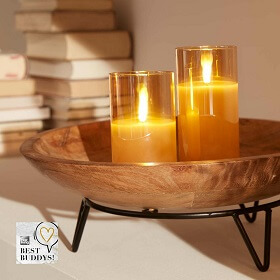 Schlae aus Naturholz mit zwei Kerzen in einem goldenen Glashalter.