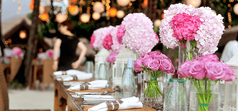 Ein hübsch eingedeckter Tisch mit Blumen, Vasen und Geschirr.
