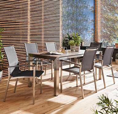 Sommer-Tischgruppe mit langem Gartentisch und netzbespannten Stühlen mit Armlehne.