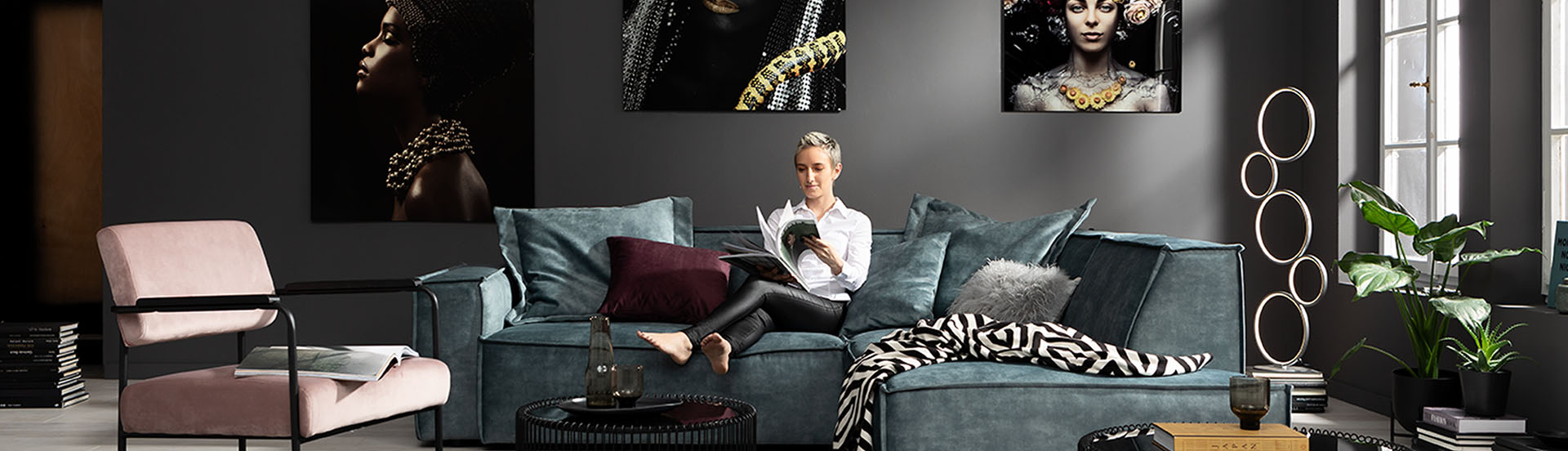 Eine Frau sitzt gemütlich auf einem Sofa und blättert duch eine Broschüre auf der Suche nach Tipps und Anregungen für ein schönes Zuhause.