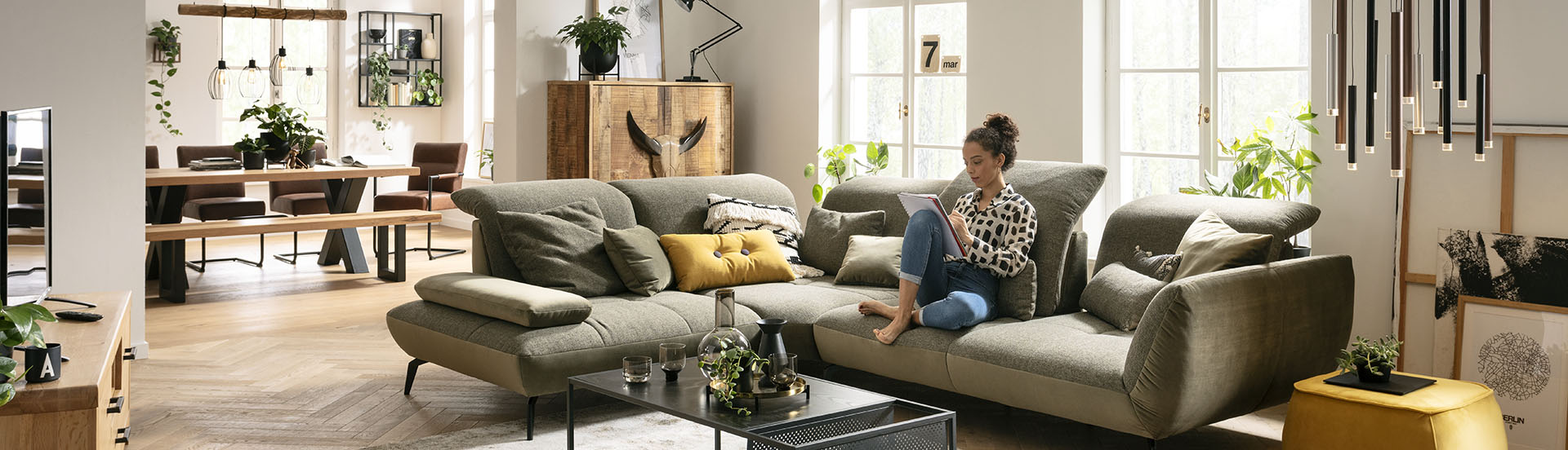 Möbel GUNST - Großzügiger Wohn-Essbereich, eine Frau sitzt auf ihrem modernen Sofa.