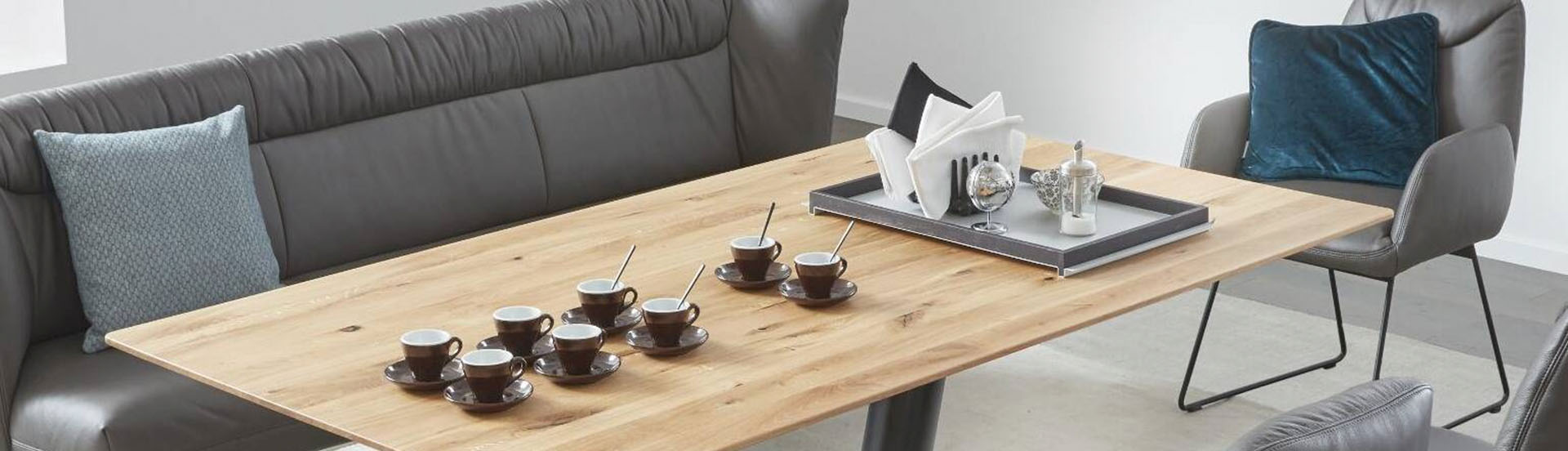 Tischgruppe mit Lederbank und gepolstertem Stuhl - auf dem Tisch 8 Espresso-Tassen und ein hübsch dekoriertes Tablett.